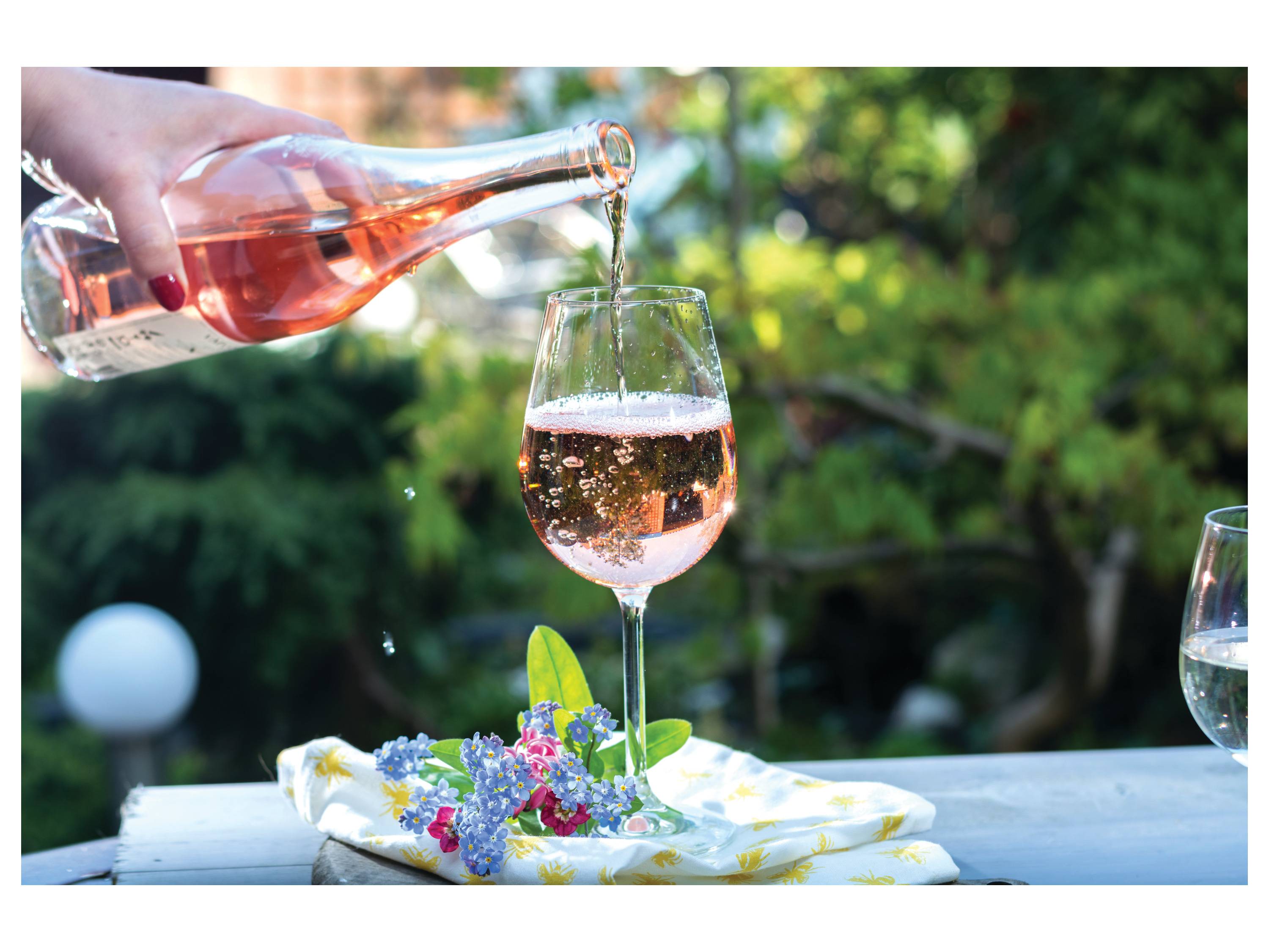 Rose wine poured into a glass outdoors.
